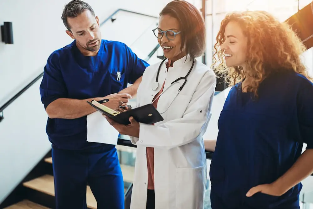 Diverse group of smiling doctors standing together in a hospital corridor discussing a patient's dignosis