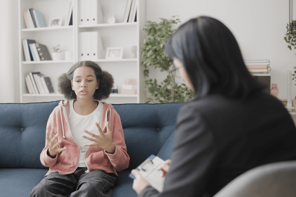 Irritated schoolgirl talking to psychoanalyst about negative feelings, advice